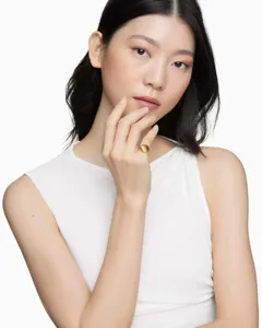 Detailed close-up of a 18K gold pleated twisted ring on Asian model's hand in French style.