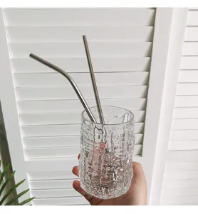 Vista detallada de pajitas reutilizables de acero inoxidable 304 en un vaso con textura