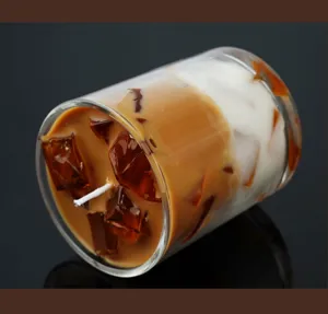 Creatieve ijskoffie geurkaars in glas met sojawas en realistische ijsblokjes decoratie thuis.