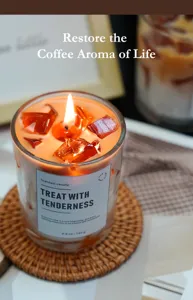 Detailopname van koffie ijsblokje geurkaars in glazen pot met warme gloeiende vlam.