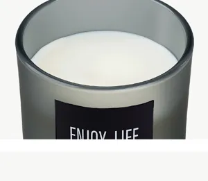 Closeup of grey frosted glass scented candle with black label detailing and smooth white soy wax.