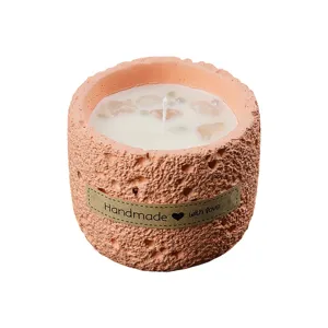 Scented candle in peach textured concrete jar with crystals and soy wax for home decor.