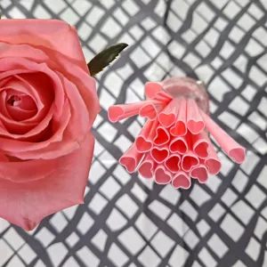 Roze hartvormige kunststof drinkrietjes in detail, perfect voor creatieve feestdrankjes.