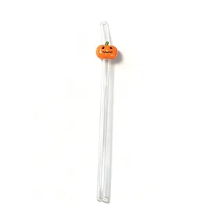 Detail shot of a transparent glass drinking straw featuring a cute 3D orange pumpkin decor.