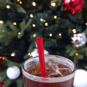 Close-up van een rood hartvormig rietje in een koud drankje tegen een feestelijke kerstachtergrond.