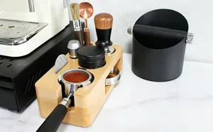Detailed view of wooden coffee tamper station set with distributor and espresso tools on counter.