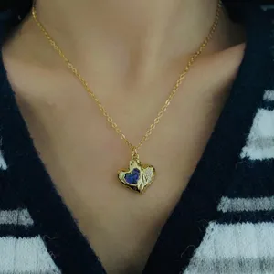 Detailed close-up of heart-shaped gold necklace with blue zircon and small stones.