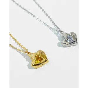 Close-up detail of gold and silver heart necklaces featuring inlaid zircon stones