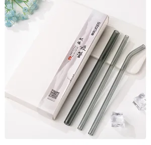 Detail view of grey heat-resistant glass straws set with elegant packaging box and ice decor.
