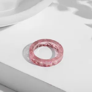 Detaillierte Nahaufnahme eines rosa transparenten Harzrings mit echten getrockneten Blüten.
