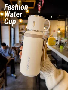 Detailed view of cream 316 stainless steel thermos cup with strap held in a cozy cafe