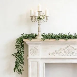 Realistic artificial olive leaf garland draped over a white vintage fireplace mantel