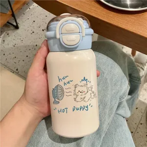 Mano che tiene una simpatica borraccia termica crema con illustrazione di cucciolo