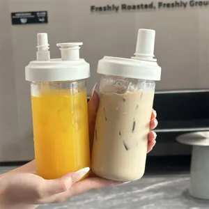 Detail view of two portable plastic straw cups filled with orange juice and milk tea.