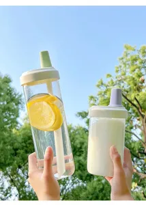 Two portable clear plastic straw water bottles shown against a sunny nature background