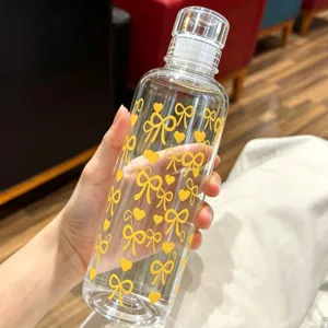 Close-up of a clear plastic water bottle with yellow bow patterns held by hand