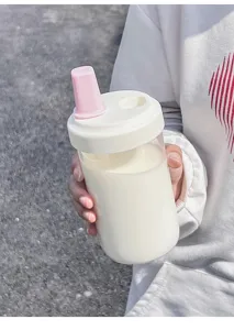 Close-up of a minimalist portable plastic water bottle with pink straw nozzle held in hand outdoors