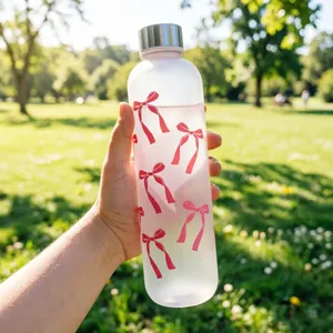 Detailed shot of frosted plastic water bottle with cute red bow ribbon pattern outdoors