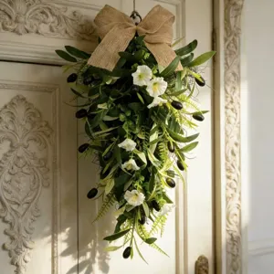 Detail of an olive teardrop wreath with white flowers and a rustic burlap bow