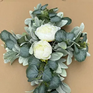 Detailed view of artificial white peony cross wreath featuring dusty green eucalyptus leaves