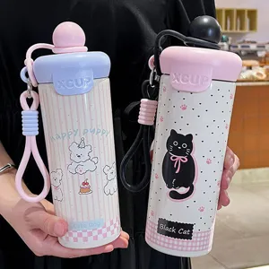 Close-up detail view of cute cartoon stainless steel thermos cup with portable strap and straw.