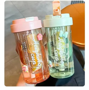 Close-up of two colorful portable plastic water bottles with straws and cute 3D charms.