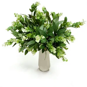 Close-up of artificial olive and eucalyptus branches arranged in a white ceramic vase