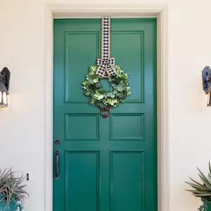 Beautiful eucalyptus wreath with black and white checkered ribbon on a green front door