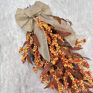 Detail view of autumn teardrop wreath with orange berries and burlap bow decoration.
