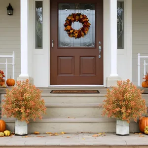 Two artificial autumn eucalyptus bushes with pumpkins on a house porch for home decor