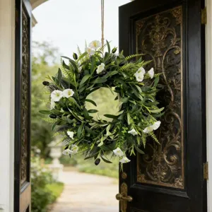 Detailed view of artificial olive wreath with white flowers on a vintage black door