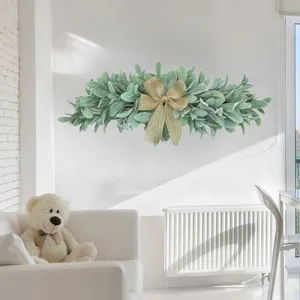 Artificial green leaf wreath swag with burlap bow on a white wall in a living room
