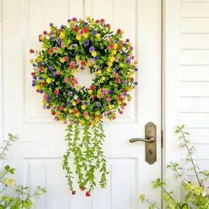 Detailed view of a vibrant eucalyptus wreath with colorful flowers on a white wooden door