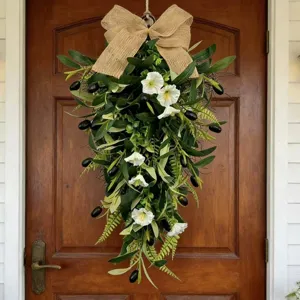 Detailed view of olive teardrop wreath with white flowers and burlap bow on door