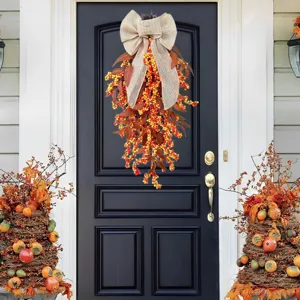 Autumn berry teardrop wreath with burlap bow hanging on a black front door