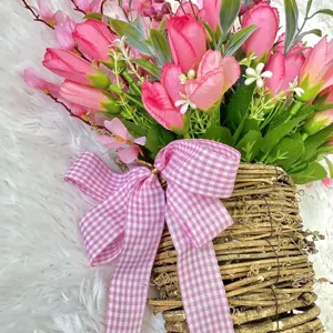 Detail shot of artificial pink tulips in a rustic woven basket with pink checkered bow