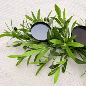 Close-up of artificial olive branch candle holder with black iron plates on white fabric