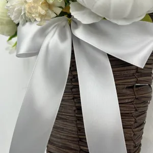 Detailed macro view of an elegant white satin ribbon bow on a woven rattan flower basket