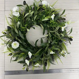 Detailed view of handmade olive wreath with white flowers and ruler for scale