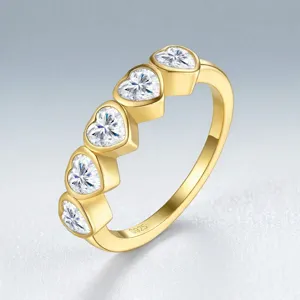Détail d'une bague en argent S925 plaqué or ornée de cinq cristaux en forme de cœur.