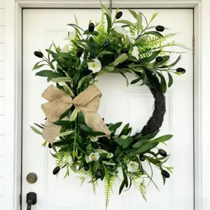 Detailed view of an artificial olive wreath with black fruits on a white door