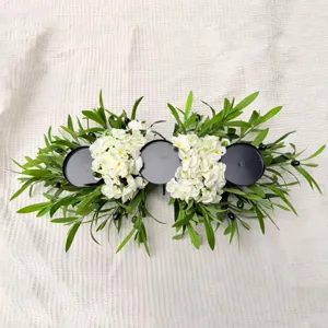 Macro top view of olive branch candle holder with white flowers and three black plates