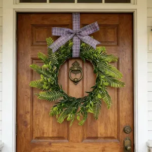 Detail of artificial Persian leaf wreath with a purple plaid bow on a wooden door