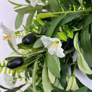 Close-up of artificial olive wreath with green leaves, black olives and white flowers
