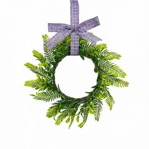 Detail view of artificial Persian fern wreath with purple checkered bow on white background