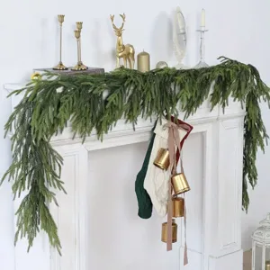 Realistic artificial Norfolk pine garland draped on a white fireplace for festive Christmas decor