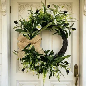 Detailed view of artificial olive wreath with white flowers and burlap bow on door
