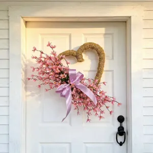 Heart-shaped spring flower wreath with pink blossoms and purple bow on a white door.