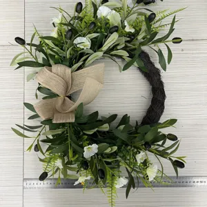 Detailed view of artificial olive wreath with white flowers and burlap bow