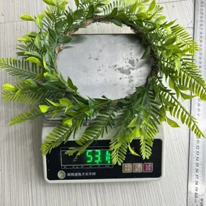 Detail of lightweight artificial green foliage wreath on digital scale weighing 53 grams.